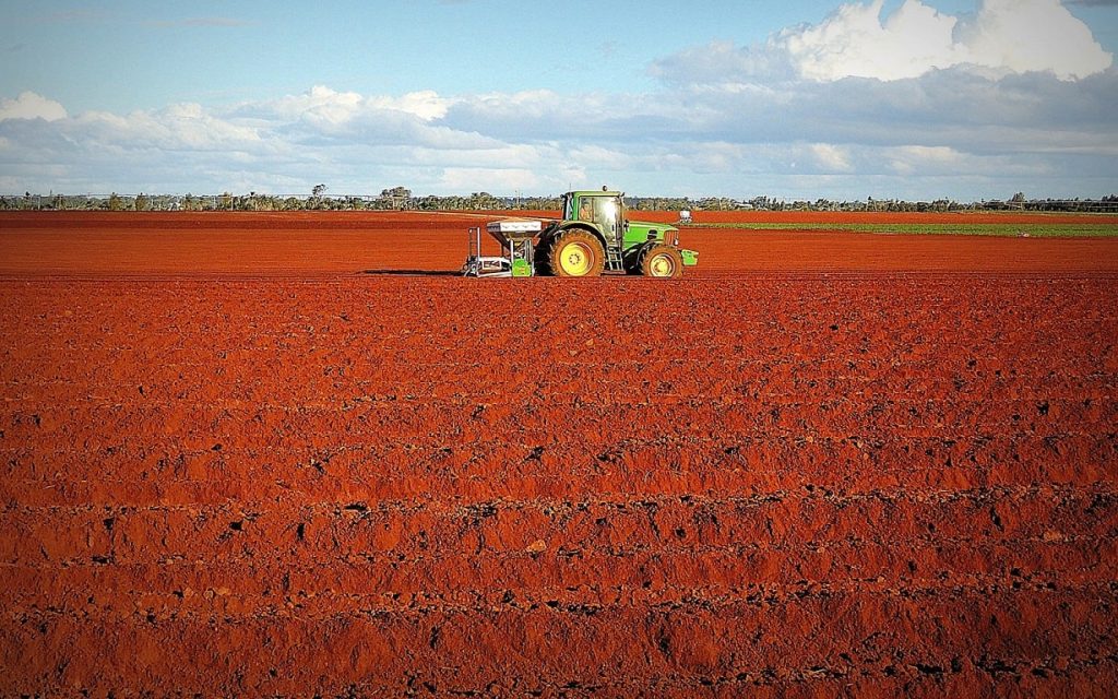 Tractor on bare field with red soil