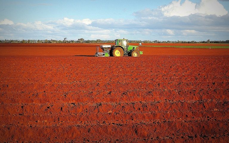 Tractor on bare field with red soil